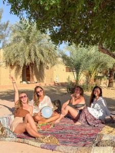 a group of women sitting on a blanket with a frisbee at Cafour House Siwa - Hot Spring in Siwa