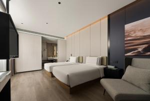 ein Hotelzimmer mit zwei Betten und einem Fernseher in der Unterkunft 上海静安寺西康路亚朵酒店 in Shanghai