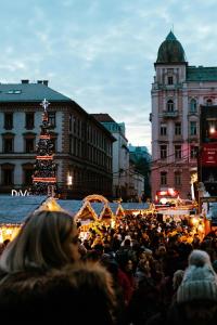 a crowd of people standing in front of a christmas tree at Three Corners Avenue Hotel in Budapest