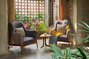 two chairs and a table on a porch with plants at SaffronStays Ashfield - 5BHK Eco-Farmhouse with Pools, Jacuzzi, Lawn & Games Room in Nashik