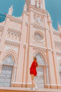 a woman in a red dress standing in front of a church at ORANGE Hotel - near Dragon Bridge, In the Heart of the City, Warm as Home in Da Nang