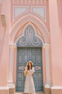 a woman wearing a hat standing in front of a building at ORANGE Hotel - near Dragon Bridge, In the Heart of the City, Warm as Home in Da Nang