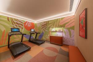 ein Fitnessstudio mit zwei Laufbändern und einer farbenfrohen Wand in der Unterkunft Orange Hotel Chengdu Wenshuyuan Subway Station in Chengdu