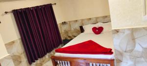 Un dormitorio pequeño con una cama con una almohada de corazón rojo. en Nakshatrahomestay, en Vattavada