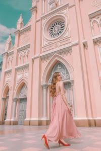 a woman in a pink dress walking in front of a building at ORANGE Hotel - near Dragon Bridge, In the Heart of the City, Warm as Home in Da Nang +27 photos