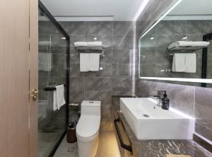 een badkamer met een wastafel, een toilet en een spiegel bij Starway Hotel Shanghai Hongqiao National Exhibition and Convention Center Beiqing Road in Shanghai +17 foto's