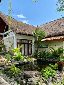 a house with a koi pond in front of it at Omnni Villa Borobudur in Borobudur