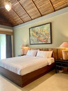 a bedroom with a large bed and a painting on the wall at Omnni Villa Borobudur in Borobudur +60 photos