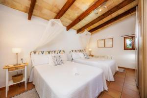 due letti in una stanza con soffitti in legno di Finca Rural Es Pujol a Sóller Altre 25 foto
