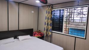 une chambre avec un lit blanc et une fenêtre dans l'établissement Rr resort, à Araku