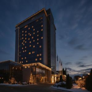 un grande edificio con luci di Natale davanti di VILNIUS PARK PLAZA HOTEL, Restaurant & Terrace, Panorama Bar, Conference & Banquet Center a Vilnius