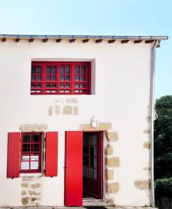 a white house with red doors and windows at Le refuge du prieuré - Les Gîtes de la Côte d'Amour in Batz-sur-Mer