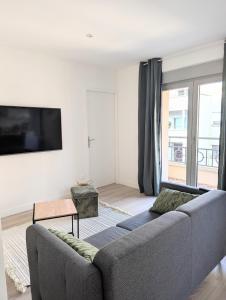 een woonkamer met een bank en een tv bij ERA - Optional parking in Romans-sur-Isère