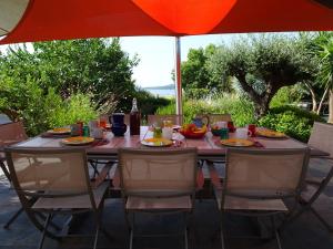 a dining table with chairs and an umbrella at Les Voiles in Pinarellu