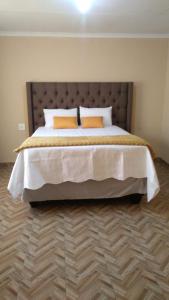Royal Gidlas Guesthouse في Saulspoort: غرفة نوم مع سرير كبير مع وسادتين برتقاليتين