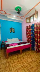 a bedroom with a bed with a blue wall at New Yamunotri homestay by Preet rS in Barkot