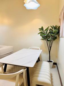 a white table and chairs in a room with a potted plant at Cloud Cinema by Kozy Mood near BGC in Manila