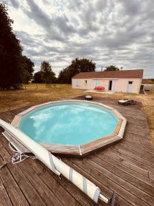 ein großer Pool auf einer Holzterrasse mit einem Haus in der Unterkunft Le HAMEAU 1936 Gîte des Milanaïs in Cherveux