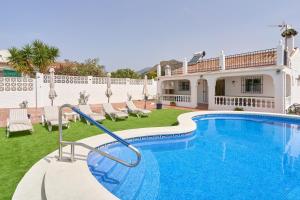 una piscina con sedie e una casa di Villa Grayce a Frigiliana