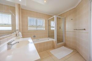 a bathroom with a sink and a shower and a tub at Luxury Ocean View Beachfront 2 bed apartment -206 The Waves, Blouberg, Cape Town in Bloubergstrand +34 photos
