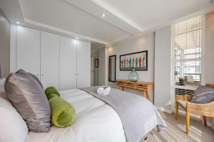 a bedroom with a large white bed and a table at Luxury Ocean View Beachfront 2 bed apartment -206 The Waves, Blouberg, Cape Town in Bloubergstrand