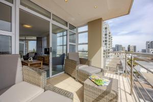 an apartment balcony with furniture and views of the city at Luxury Ocean View Beachfront 2 bed apartment -206 The Waves, Blouberg, Cape Town in Bloubergstrand