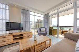 a living room with a television and a couch at Luxury Ocean View Beachfront 2 bed apartment -206 The Waves, Blouberg, Cape Town in Bloubergstrand