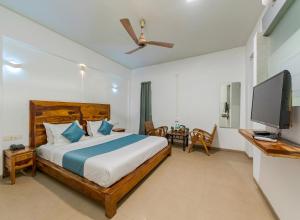 a bedroom with a bed and a flat screen tv at Hotel Zorba Inn in Kolhapur