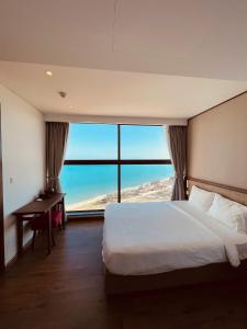 Schlafzimmer mit einem Bett, einem Schreibtisch und einem großen Fenster in der Unterkunft Minh Tân Apartment Mandala in Mui Ne