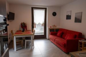 un soggiorno con un divano rosso e un tavolo di Casa da Normi a Valdisotto