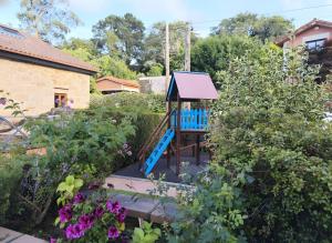 a garden with a blue playground in the middle of flowers at Holibai, Chuliña, Vacaciones Familiares en Baiona, Espacio, Piscina y Playa a un Paseo in Baiona