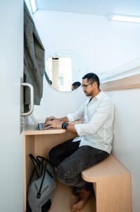 a man sitting at a desk in front of a mirror at Bobopod Tanah Abang, Jakarta in Jakarta