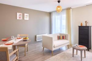 ein Wohnzimmer mit einem Tisch und einem weißen Stuhl in der Unterkunft Zenitude Quality Aparthotel Le Havre les docks in Le Havre