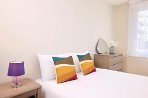 ein Schlafzimmer mit einem weißen Bett und bunten Kissen in der Unterkunft Zenitude Quality Aparthotel Le Havre les docks in Le Havre + 26 Fotos