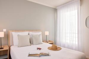 1 dormitorio con 1 cama con sombrero y 2 libros en Zenitude Quality Aparthotel Cherbourg, en Cherbourg-en-Cotentin