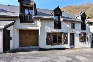 ein großes weißes Haus mit braunen Garagentoren in der Unterkunft Gite à Cazaux - Bagnères de Luchon in Cazaux-Layrisse