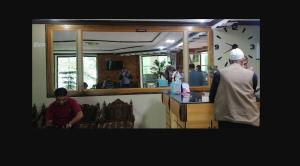 twee mannen aan een balie in een restaurant bij Khan Regency Hotel in Dargai