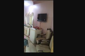 een kamer met een tv, een stoel en een spiegel bij Khan Regency Hotel in Dargai