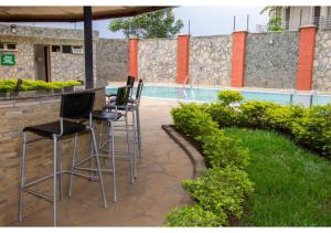 Una fila de taburetes de bar junto a una piscina. en The Pinecone Hotel Kisumu, en Kisumu