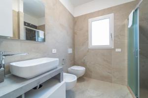 a bathroom with a sink and a toilet and a window at Brorent A & L apartment T in Golfo Aranci +19 photos