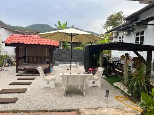 een terras met een tafel, stoelen en een parasol bij DGarden Homestay in Kuala Terengganu
