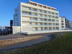 a large white building next to a grass field at Alte Teestube Schmidt 59 Rechts in Norderney