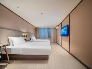een hotelkamer met twee bedden en een tv bij Hanting Hotel Chengdu Tianfu Square Subway Station in Chengdu