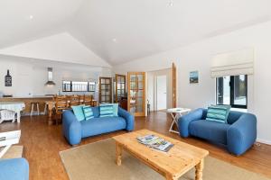 ein Wohnzimmer mit 2 blauen Stühlen und einem Tisch in der Unterkunft Beachfront Prevelly Exclusive Holiday Home in Prevelly