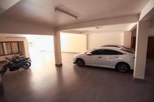大叻Hùng Phong Hotel - Near Dalat Market的一辆停放在车库的白色汽车,一辆摩托车