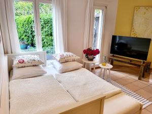 a living room with two beds and a flat screen tv at Schöne Gartenwohnung am Strand von Tegna Centovalli in Tegna