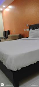 Cama en habitación de hotel con colcha blanca en Hotel bodhi Inn, en Lucknow 4 fotos más
