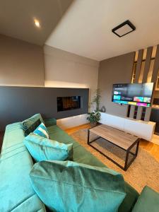 a living room with a green couch and a tv at NAR Royalton Deluxe Apartment #74 in Niš