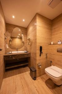 a bathroom with a toilet and a sink and a mirror at Hotel Classic Pavilion in Trivandrum