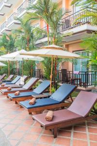 Nipa Resort, Patong Beach في شاطيء باتونغ: صف من كراسي الصالة والمظلات في الفندق